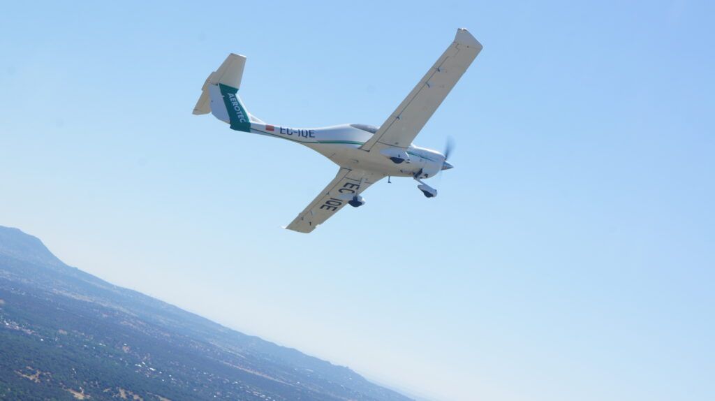 A small plane is flying in the sky over a mountain.