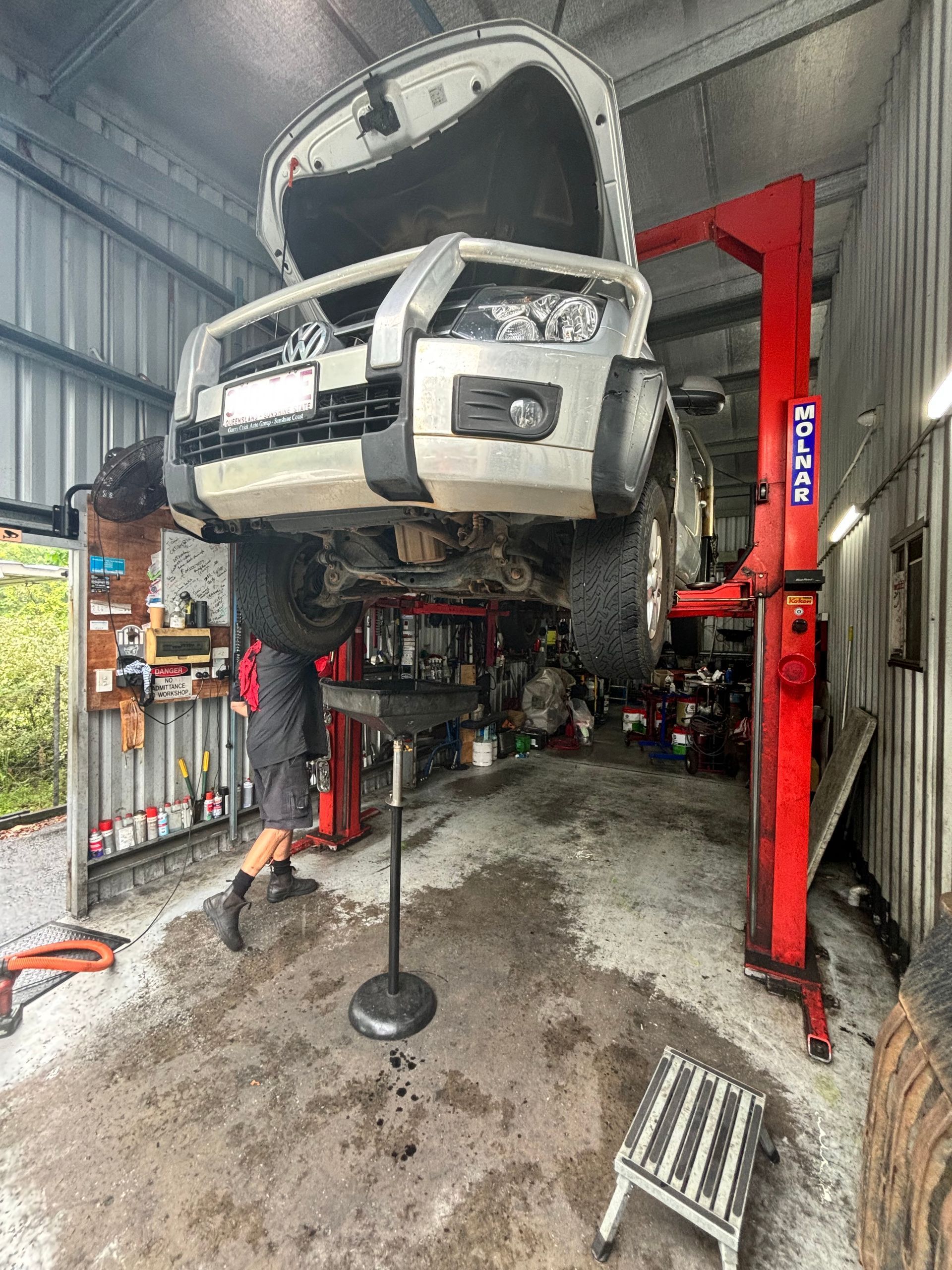 A Man Is Working On A Car In A Garage  — Coastwide Automotive Repairs In Nambour, QLD