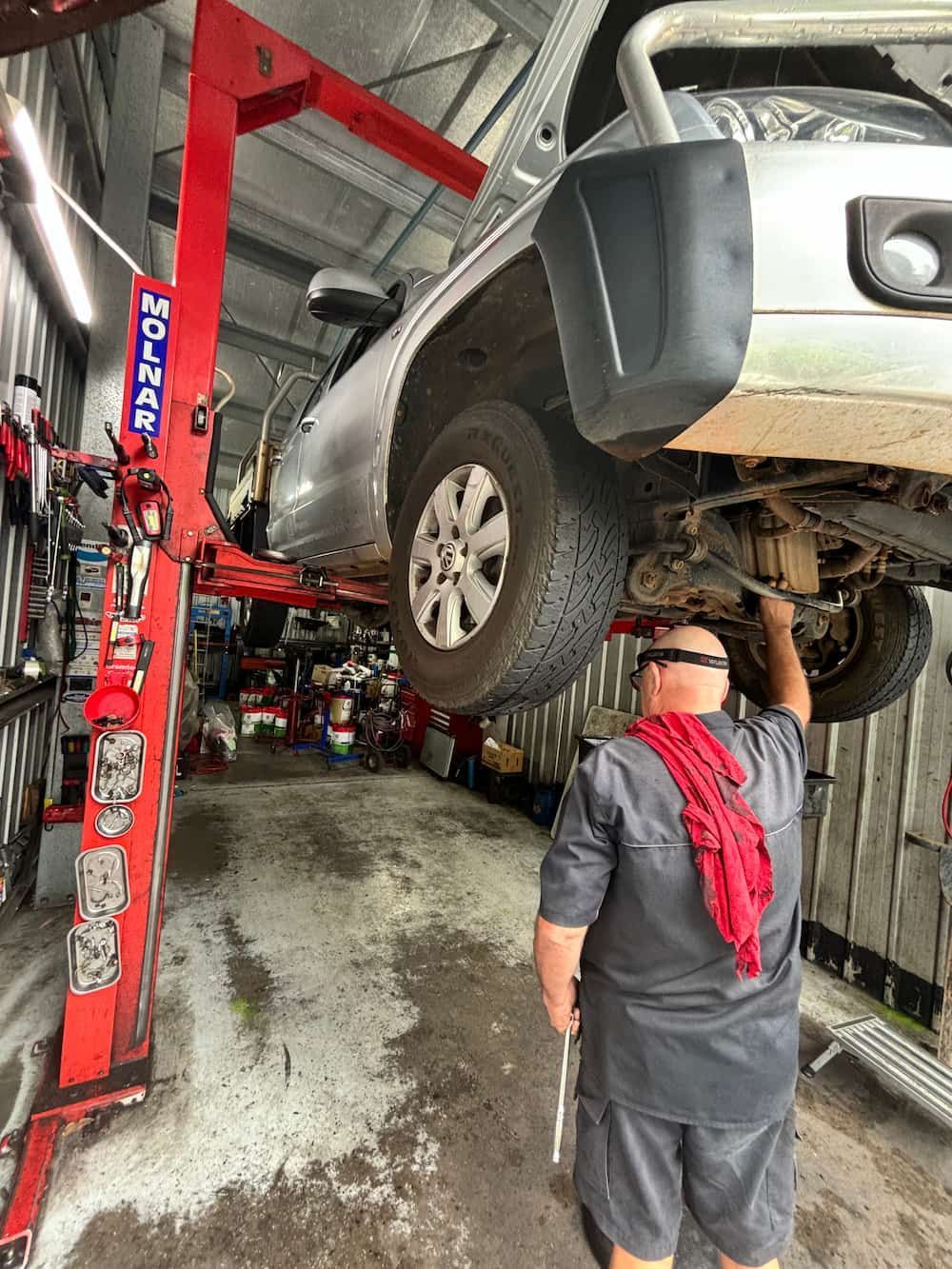A Man Is Working On The Underside Of A Car In A Garage — Coastwide Automotive Repairs In Nambour, QLD