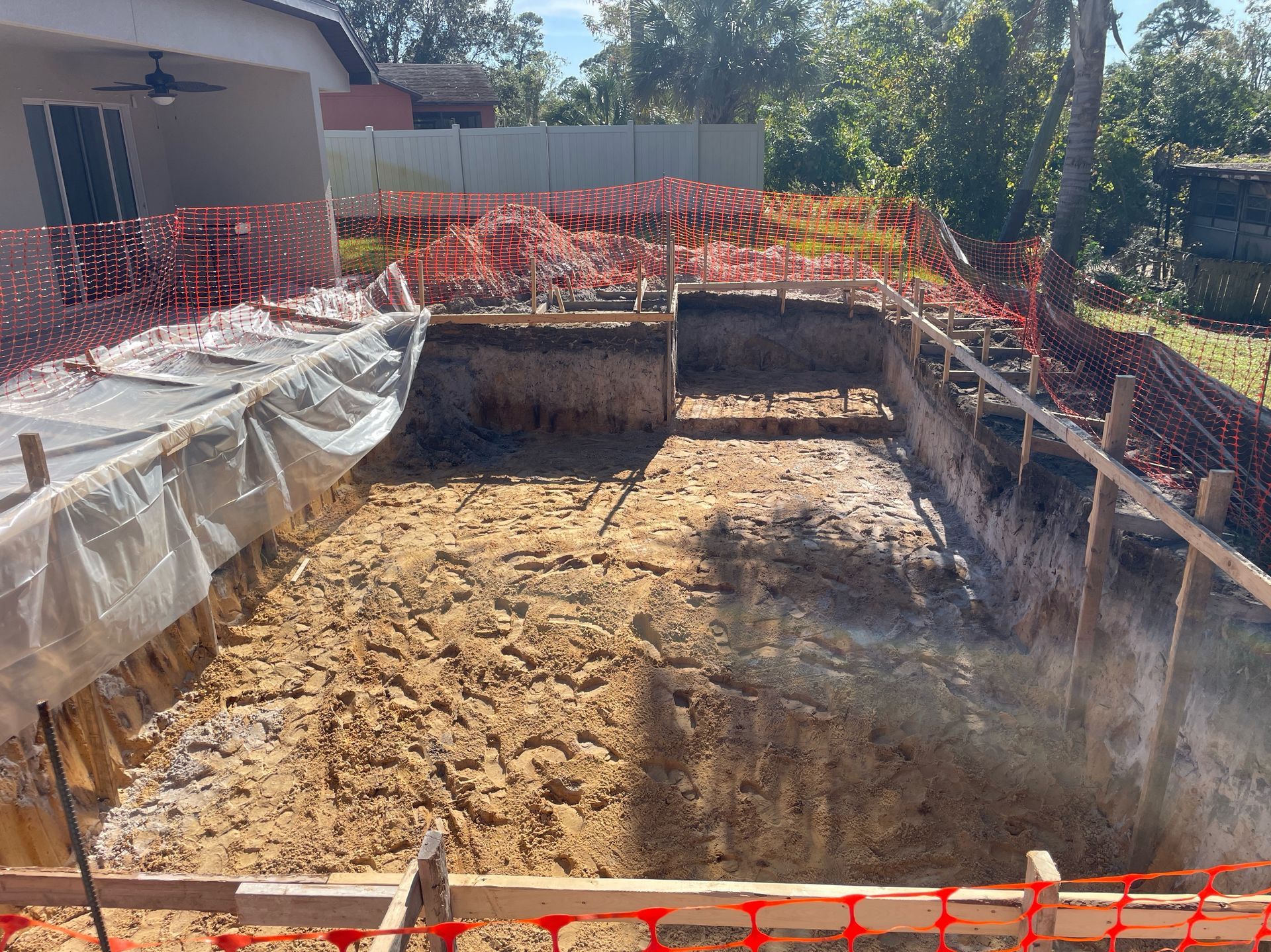 A swimming pool is being built in the backyard of a house.