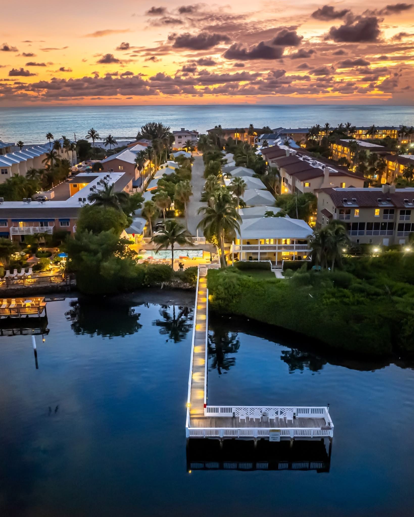 An aerial view of a dock in the middle of a body of water at sunset.