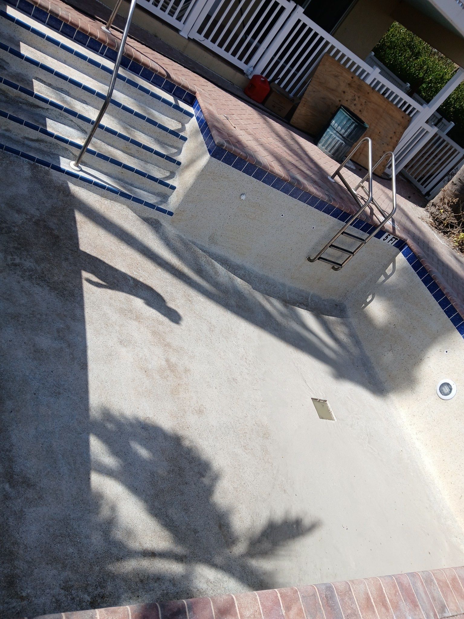 An empty swimming pool with a ladder on the side of it.