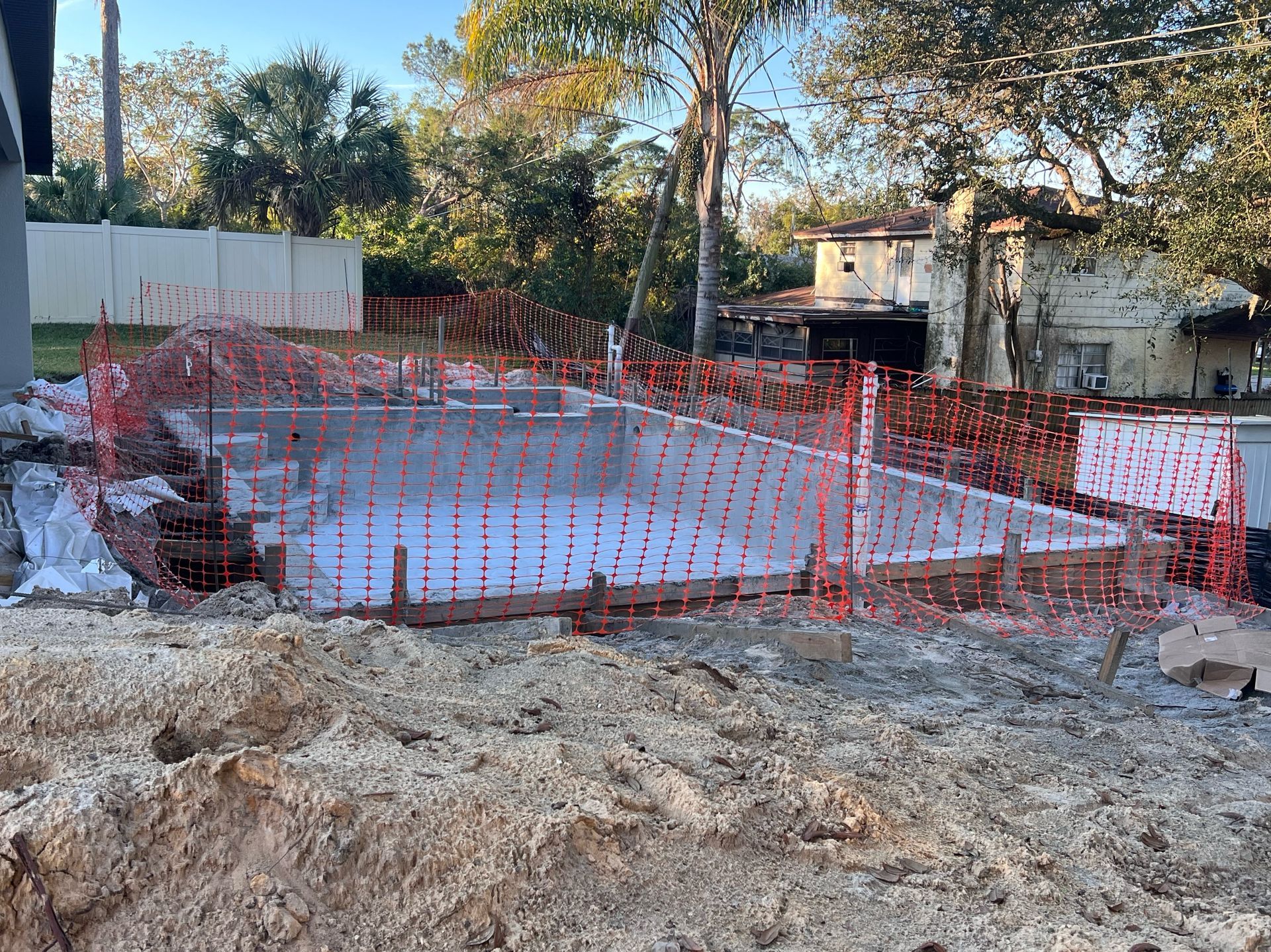 A construction site with a fence around it and a house in the background.