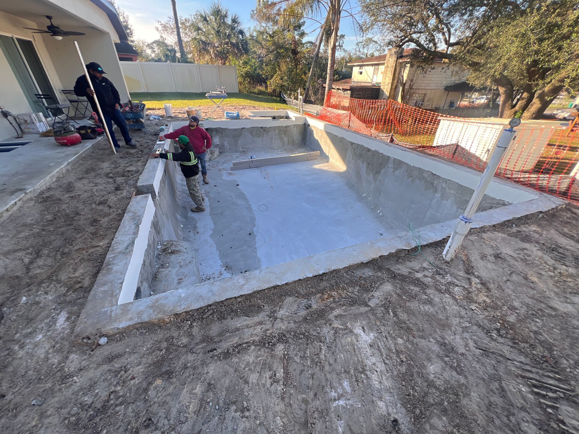 A man is working on a swimming pool in a backyard.