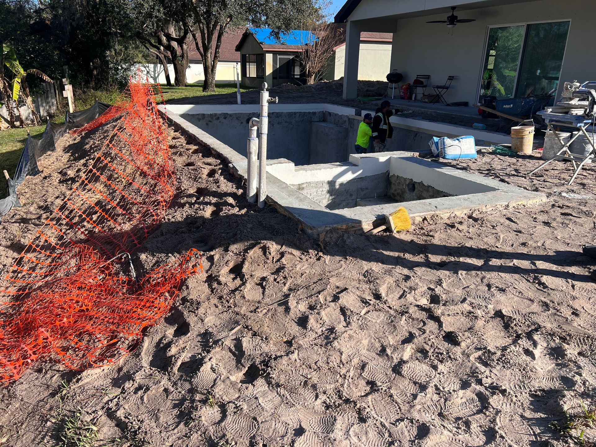 A swimming pool is being built in the backyard of a house.