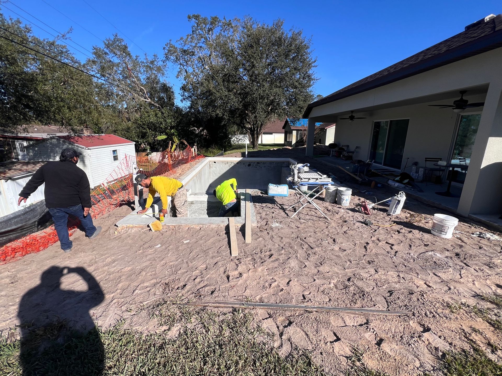 A man is standing in the dirt in front of a house.