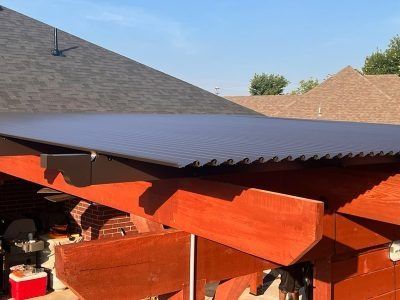 A wooden pergola with a black roof and a blue sky in the background.
