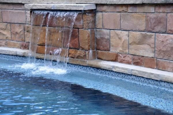 There is a waterfall in the middle of a pool.