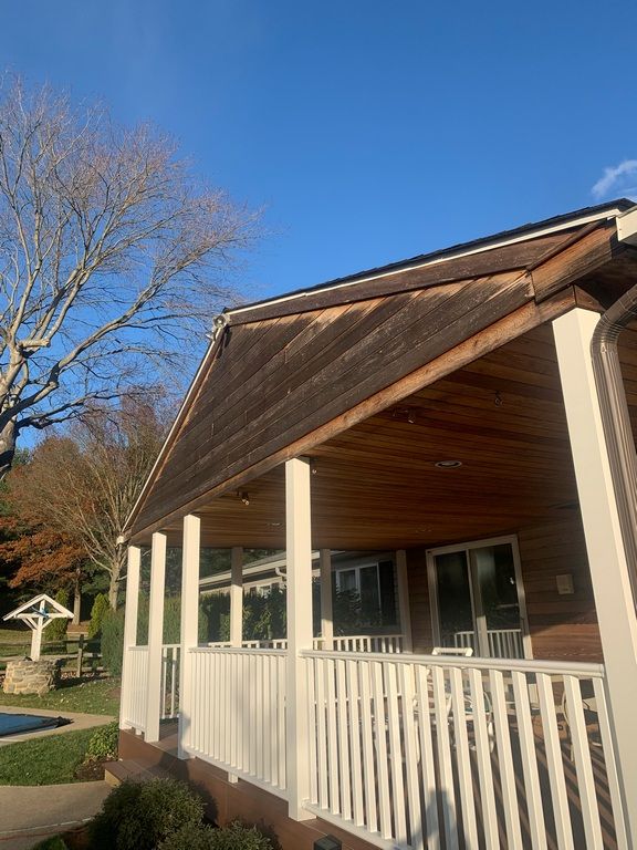 A house with a porch and a pool in the background.