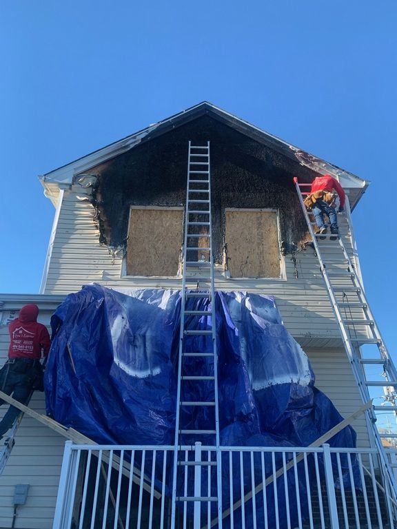 Two men are working on the side of a house.