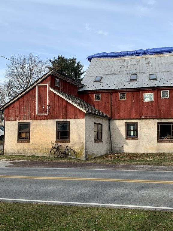 A red barn with a blue tarp on the roof.