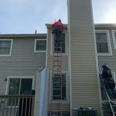 A man is standing on a ladder on the side of a house.