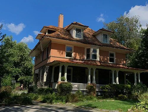 A large house with a large porch and a chimney.