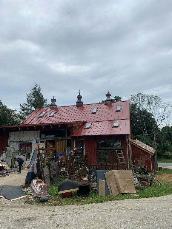 A red barn with a red roof is being remodeled.
