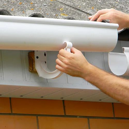 A person is fixing a gutter on a roof.