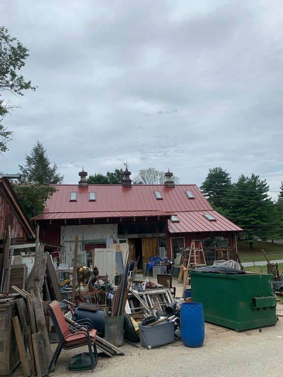 A red barn with a green dumpster in front of it.