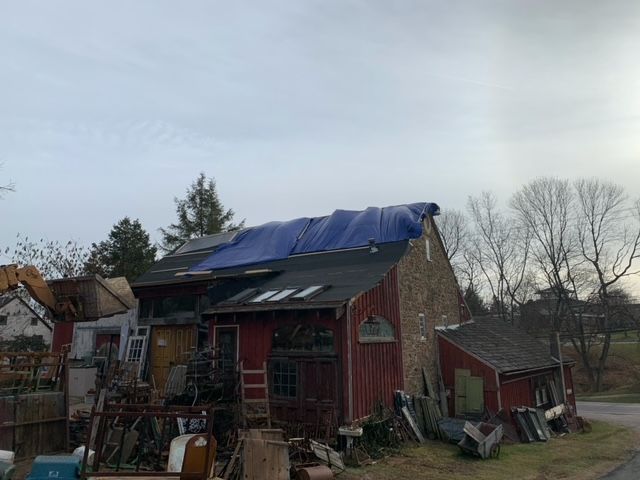 A red barn with a blue tarp on the roof.