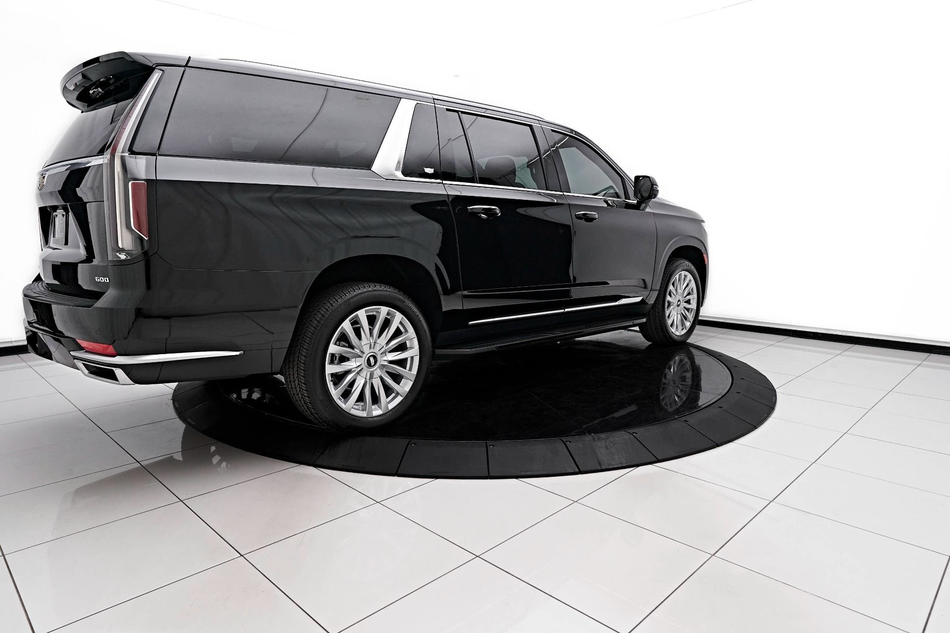 A black suv is parked on a white tiled floor in a showroom.