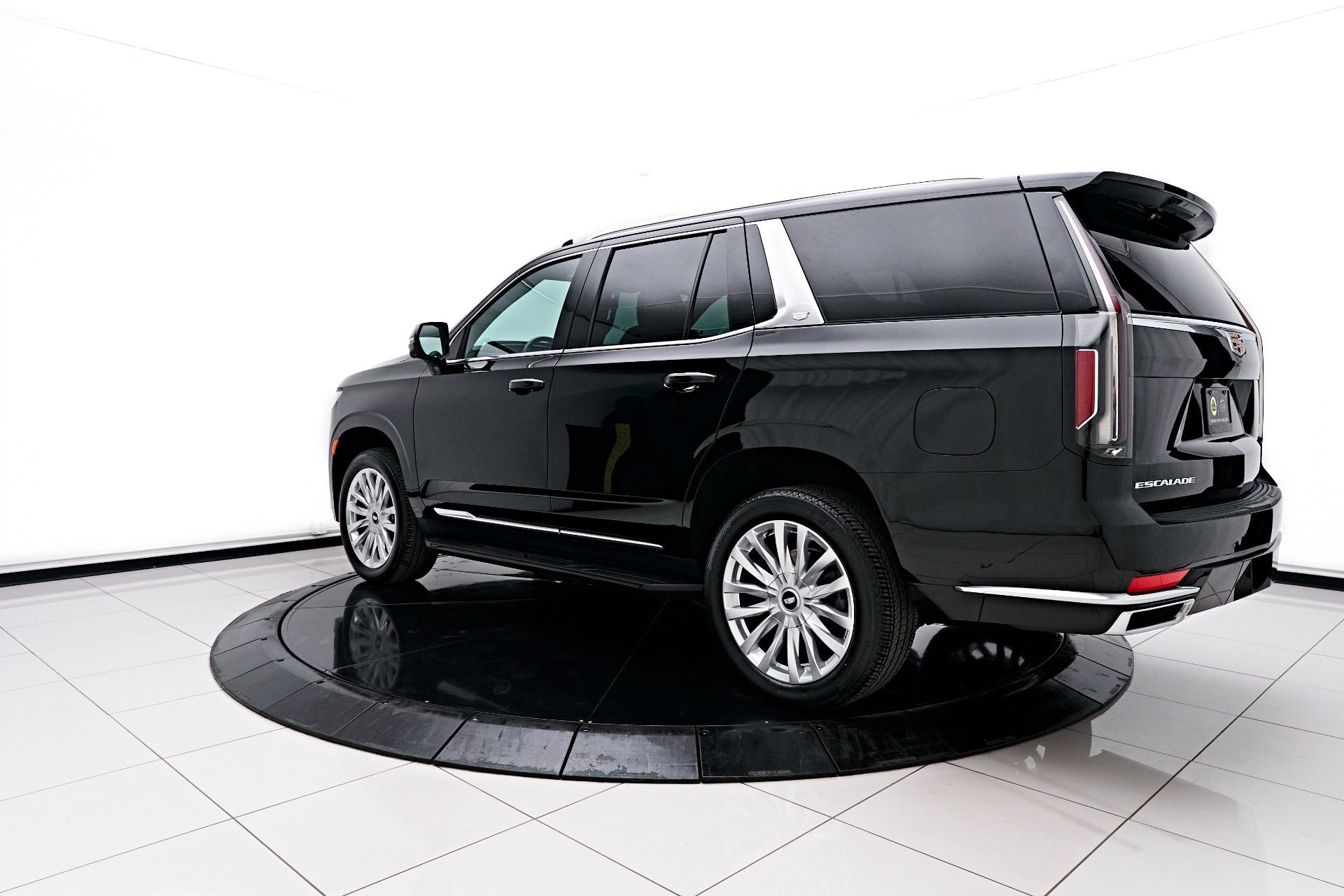 A black suv is parked on a circular display in a showroom.