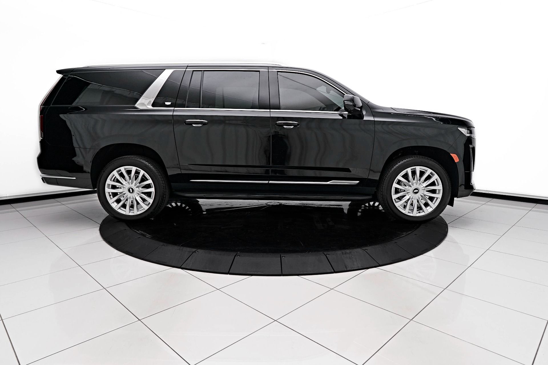 A black suv is parked on a tiled floor in a showroom.