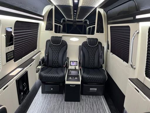 The inside of a van with two black seats and a table.