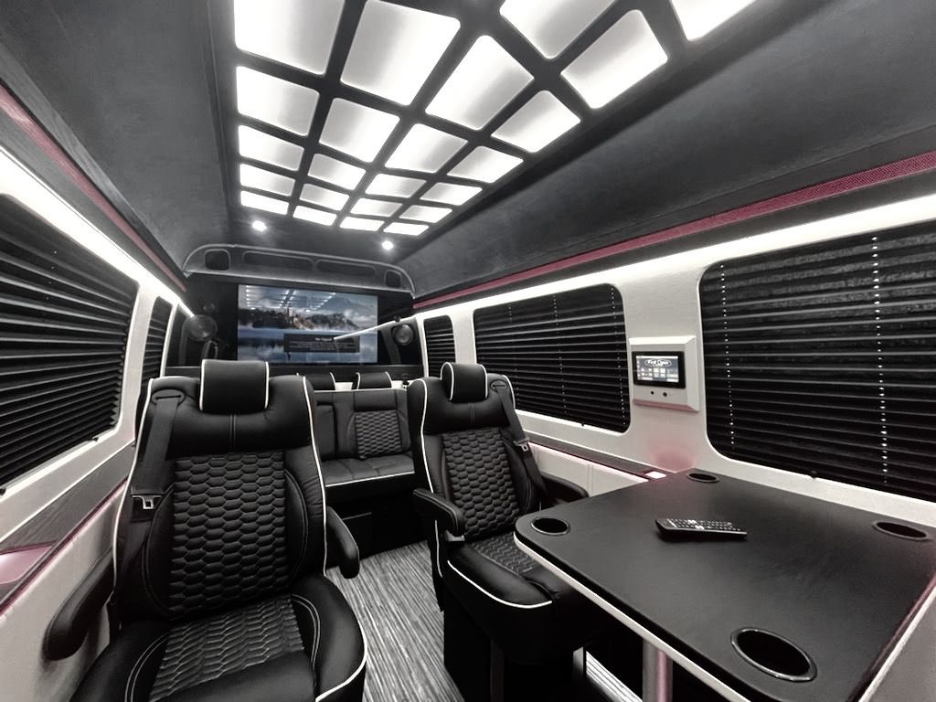 The inside of a van with black seats and a table.