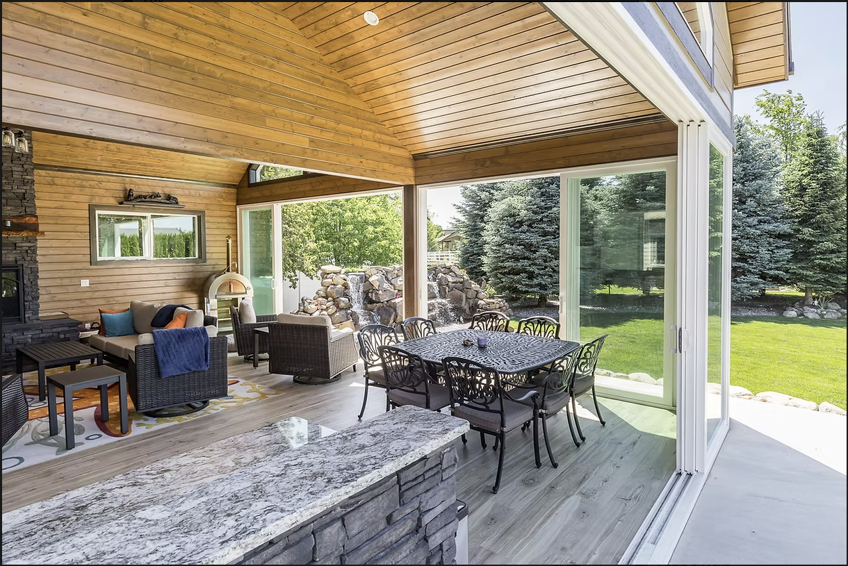 Covered outdoor patio with a dining and seating area. Sliding glass doors open to a backyard.