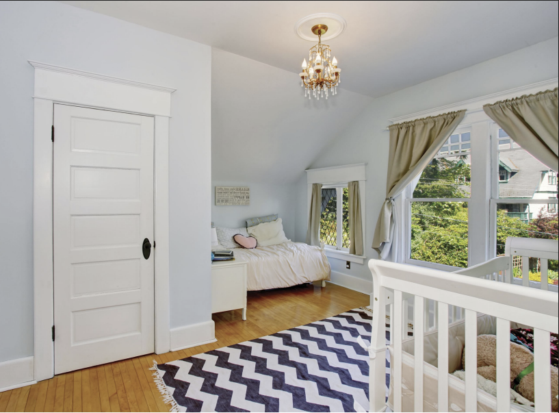 Bedroom with crib, bed, wooden floor, and a patterned rug.