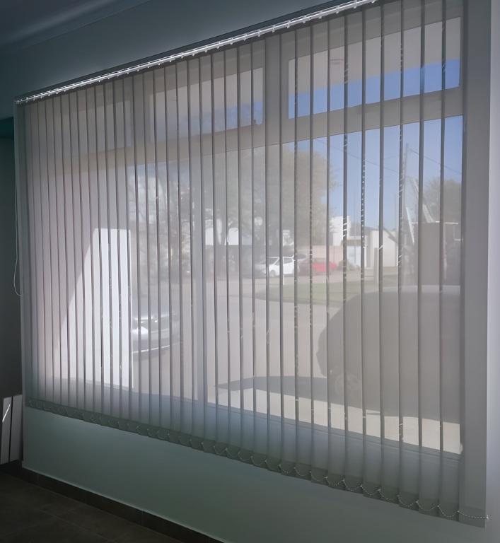 Persianas de cebra blancas que cubren una ventana en una habitación vacía, de paredes blancas.