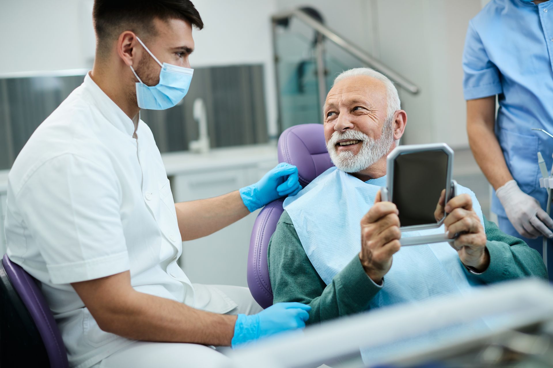 Dentist shows a smiling patient his teeth in a mirror, dental office.
