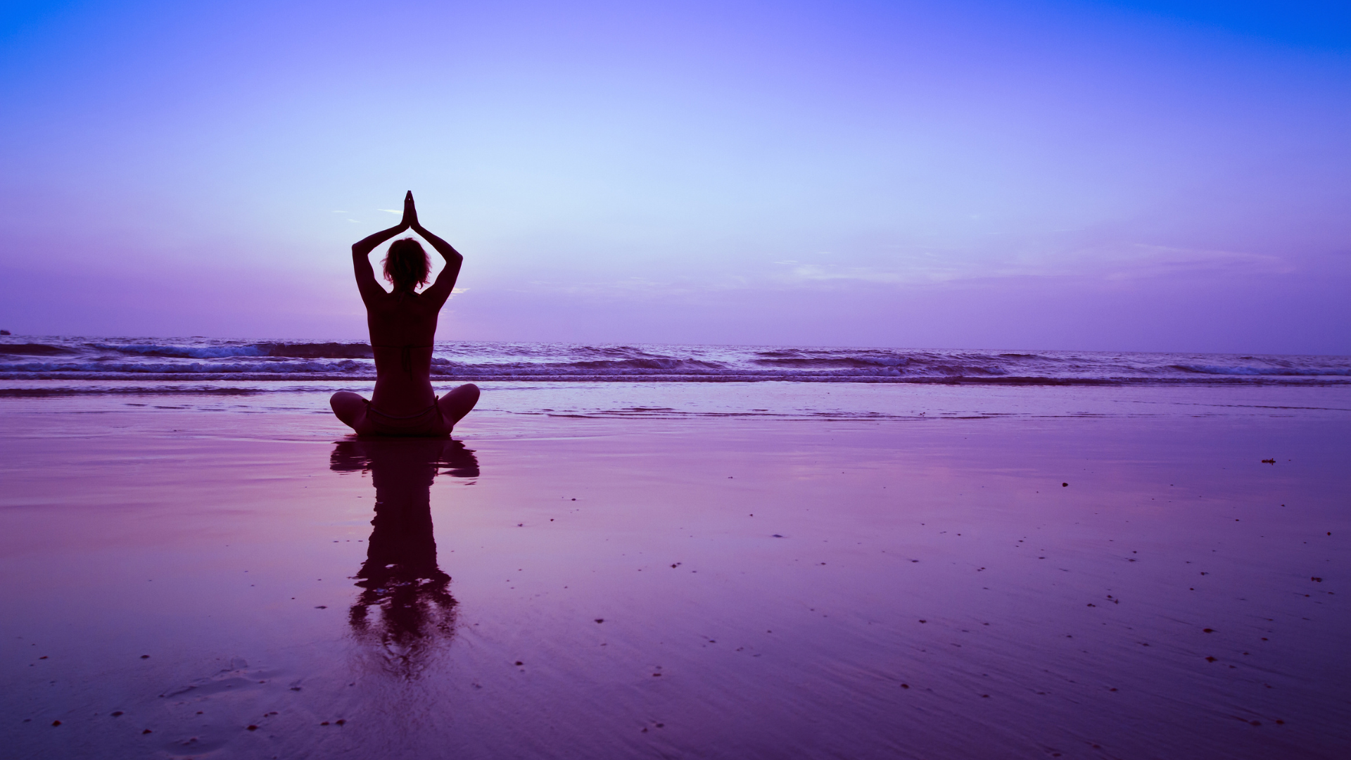 a woman is practicing yoga on the beach at sunset