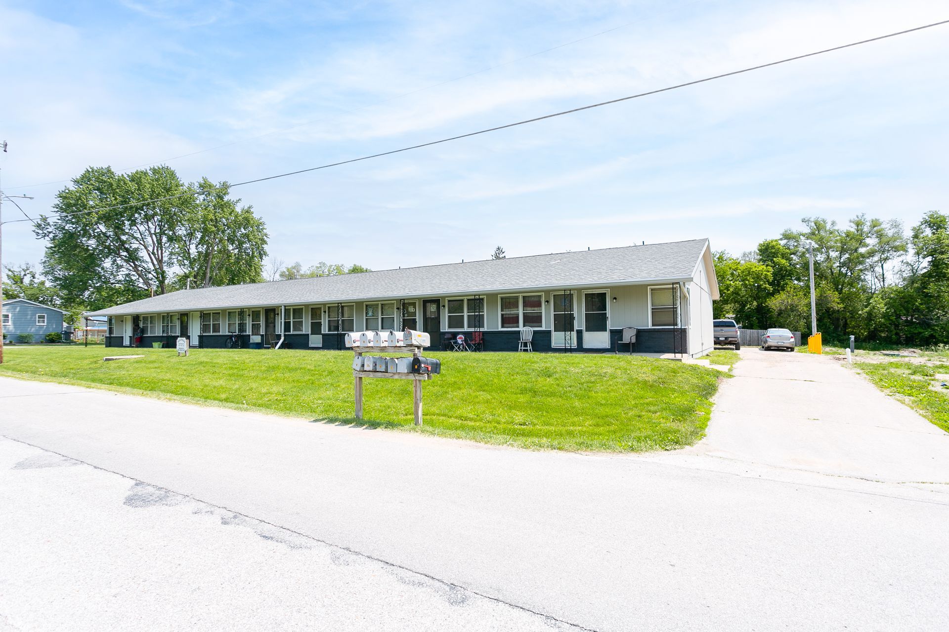 A long, low-slung apartment building with a gray roof and black and white trim, on a green lawn.