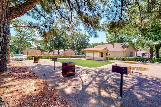 A park with a lot of trees and a house in the background.