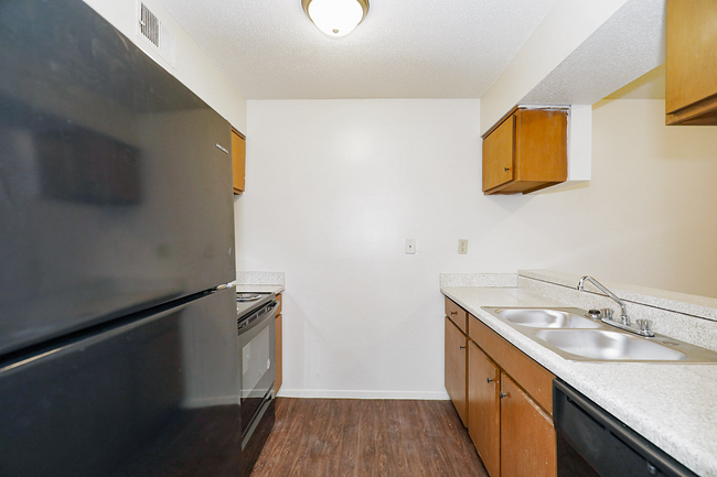 A kitchen with a black refrigerator , sink , stove and dishwasher.