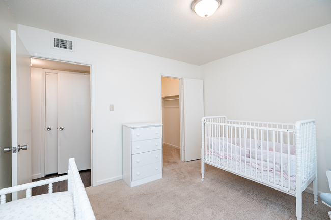 A bedroom with a crib and dresser in it