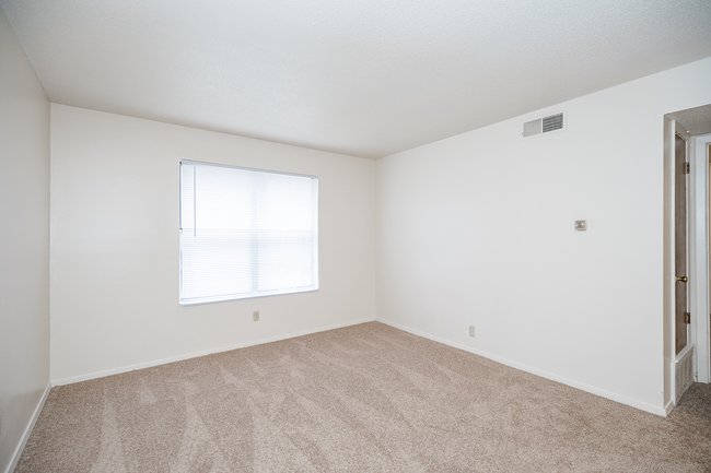 An empty bedroom with a window and carpet.