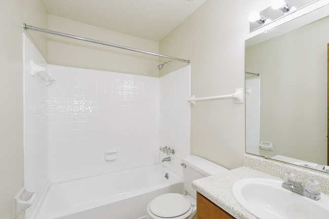 A bathroom with a tub , toilet , sink and mirror.