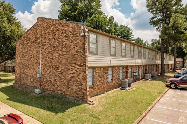 A brick apartment building with cars parked in front of it.