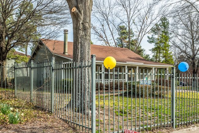 Two balloons are hanging from a metal fence in front of a house.