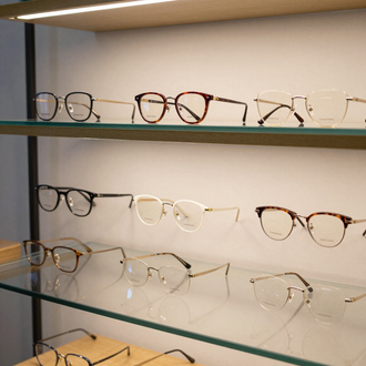 Monturas de gafas expuestas en estantes de cristal en la sala de exposición de una tienda.