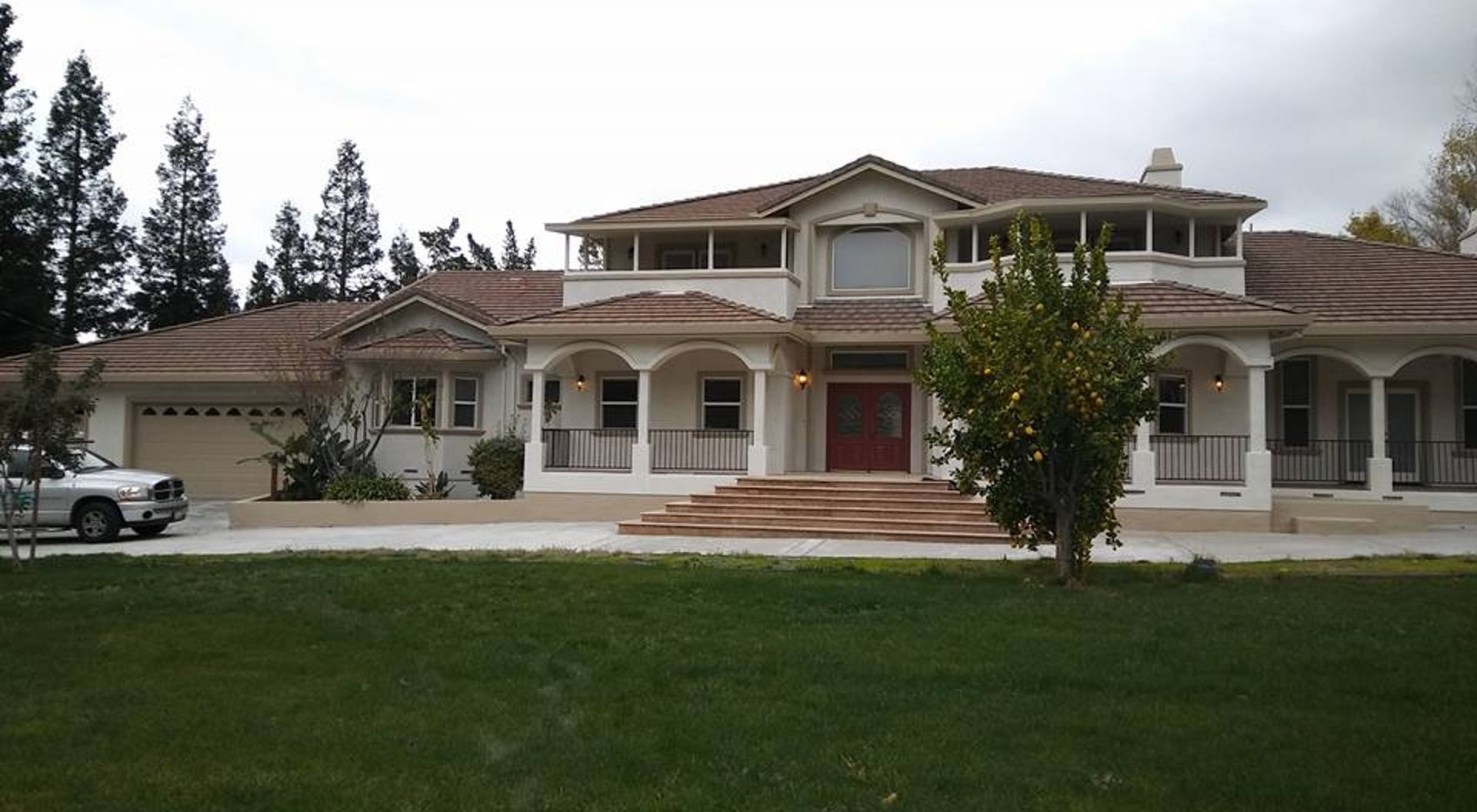 A white truck is parked in front of a large house