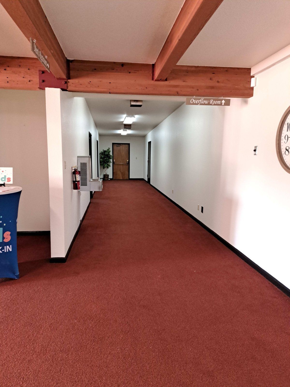 A long hallway with red carpet and a clock on the wall