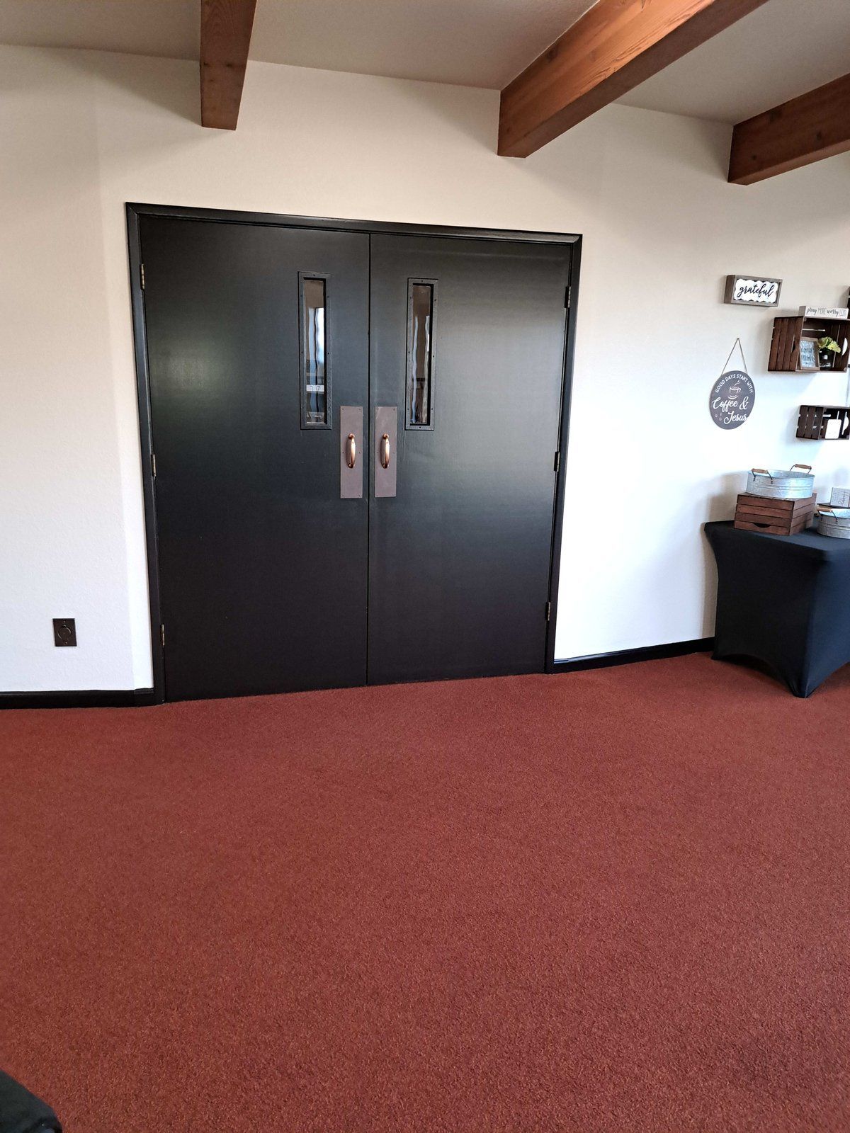 A room with two black doors and a red carpet.
