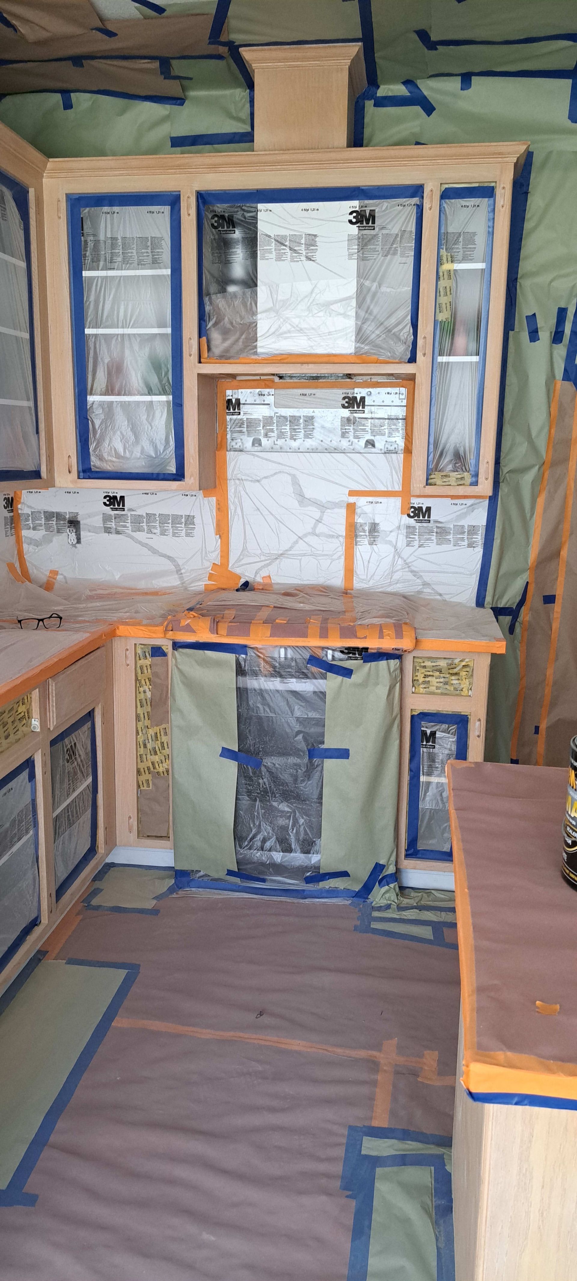 A kitchen is being painted with blue tape.