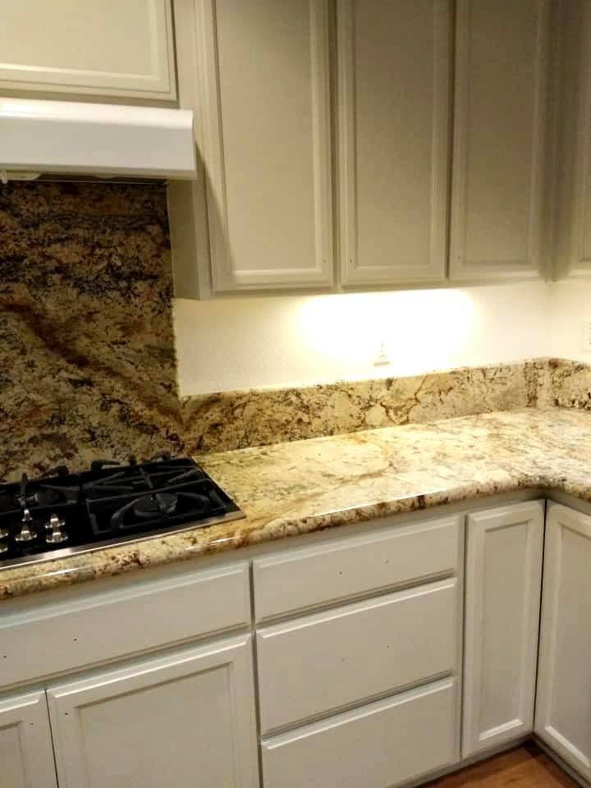 A kitchen with a stove top oven and granite counter tops.