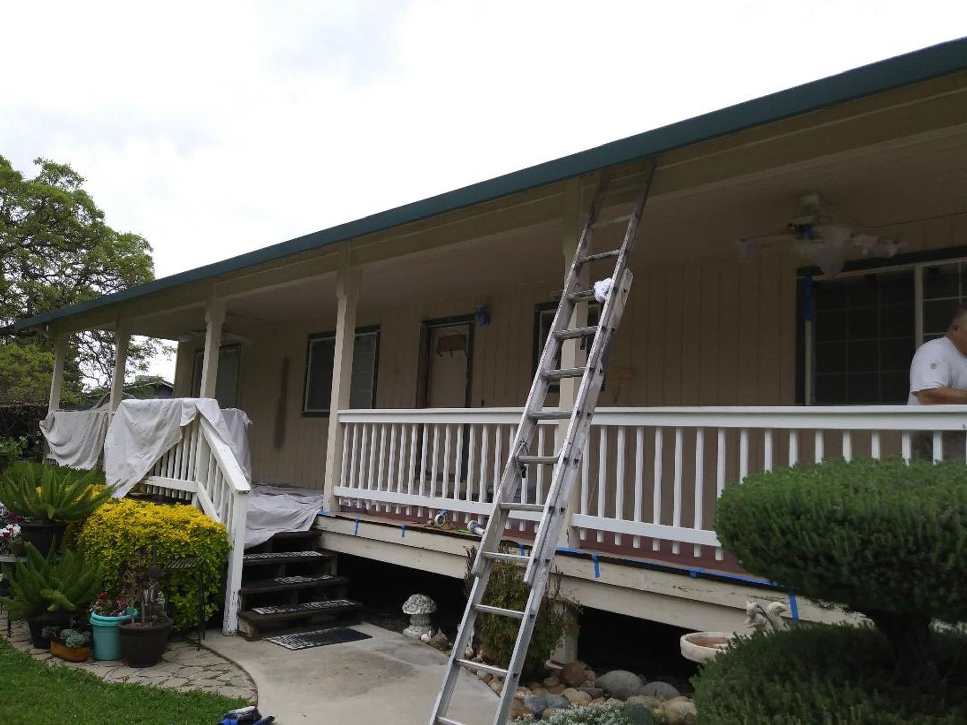 A man is standing on a porch of a house with a ladder attached to it.