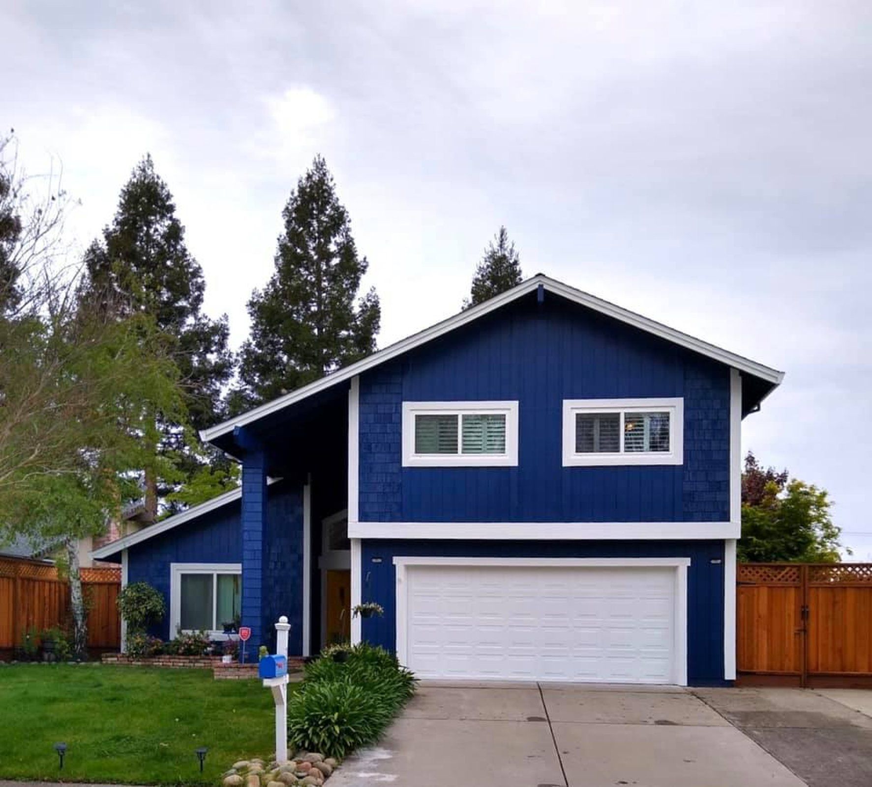 A blue house with white trim and a white garage door