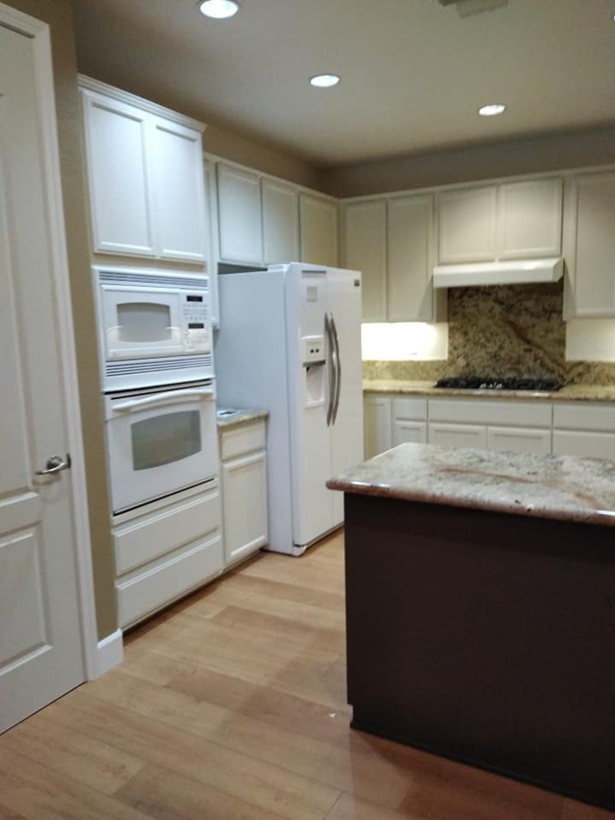 A kitchen with white cabinets a refrigerator and a microwave