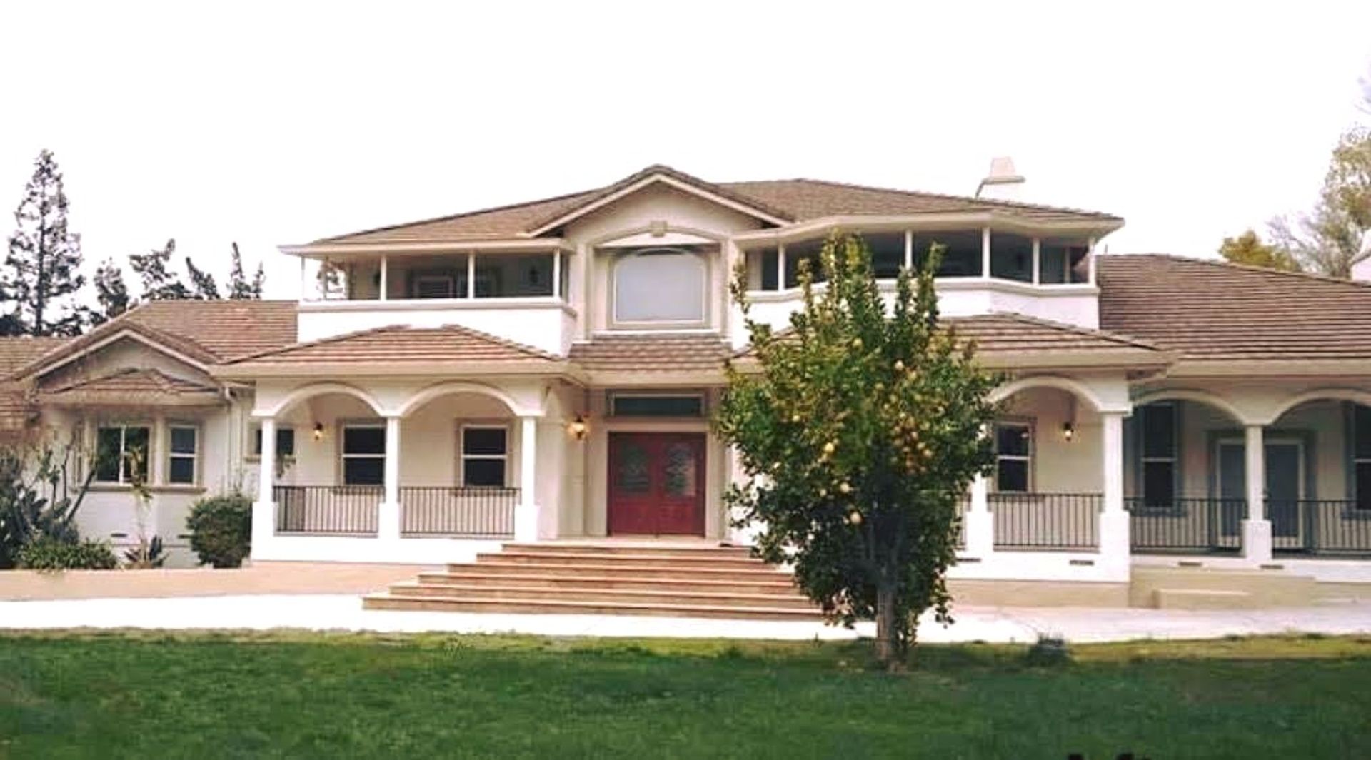 A large white house with a brown roof and a red door