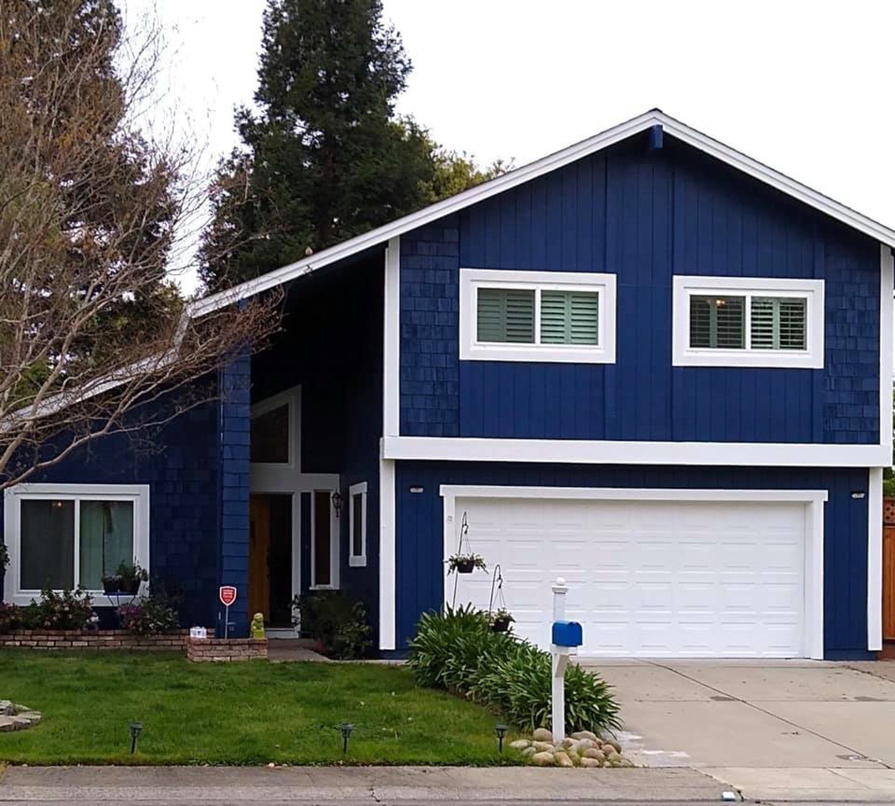A blue house with white trim and a white garage door